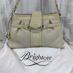 May include: A white leather Brighton handbag with a crocodile embossed design and silver hardware. The bag has a top handle and a shoulder strap.