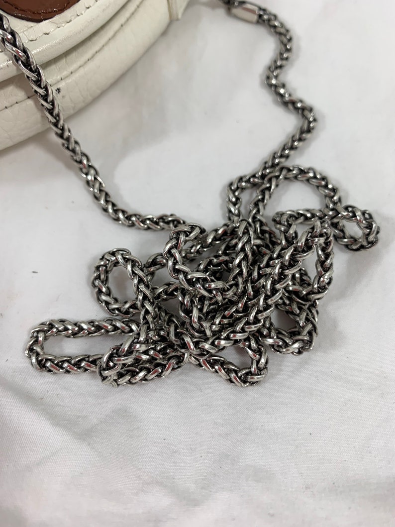 May include: A silver chain strap for a handbag. The chain is made of interwoven links and has a polished finish.