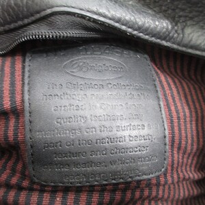May include: Close-up of a black leather tag with the text "The Brighton Collection handbags are individually crafted in China from quality leathers. Any markings on the surface are part of the natural beauty, texture and character of the leather, which make each bag unique."