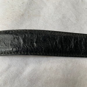 Op de afbeelding: Close-up van een zwarte leren riem met een reli&euml;fstructuur.