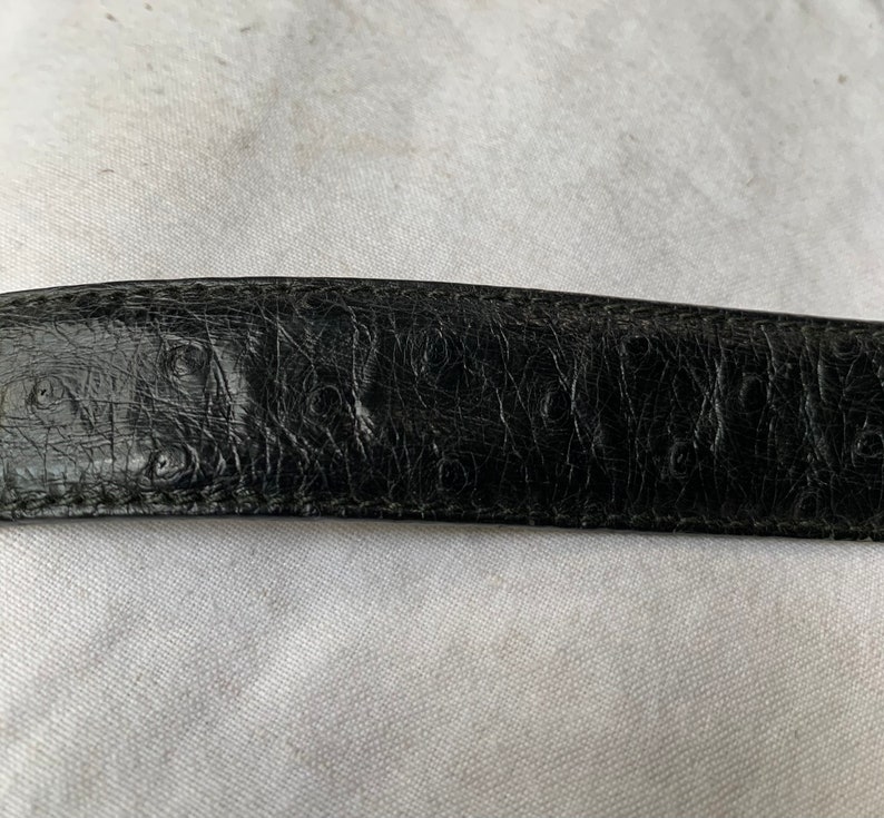 Op de afbeelding: Close-up van een zwarte leren riem met een reli&euml;fstructuur.