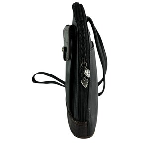 May include: Black leather crossbody bag with a brown leather bottom and a small front pocket. The bag has a zipper closure with heart-shaped charms and a long strap for wearing across the body.
