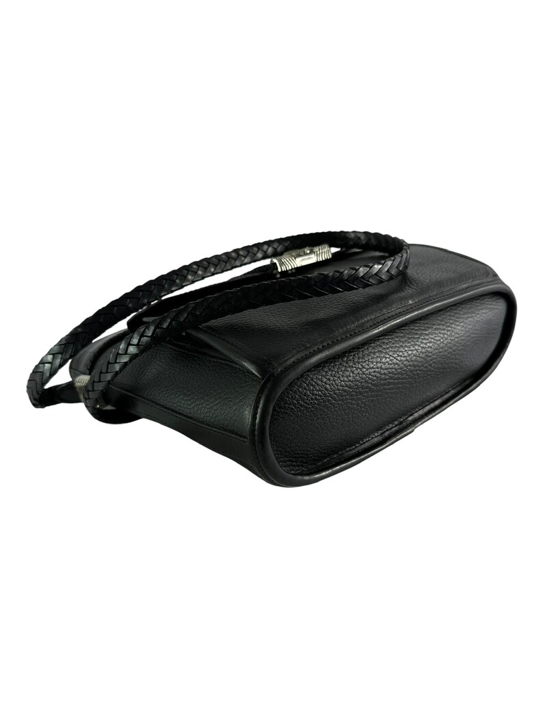 May include: Black leather crossbody bag with a braided strap. The bag has a rounded shape and a silver-toned clasp. The leather appears to have a textured grain. The strap is also black and braided.