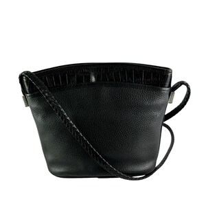 May include: Black leather crossbody bag with a textured top panel and a braided strap. The bag has a rounded shape and a small handle on the side. The bag is made of leather.