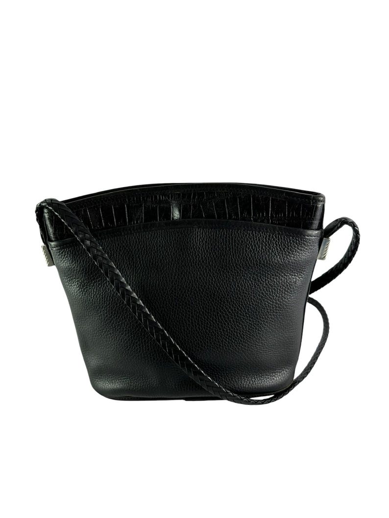 May include: Black leather crossbody bag with a textured top panel and a braided strap. The bag has a rounded shape and a small handle on the side. The bag is made of leather.
