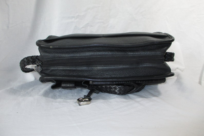 May include: Black leather handbag with a braided strap and a heart-shaped charm.