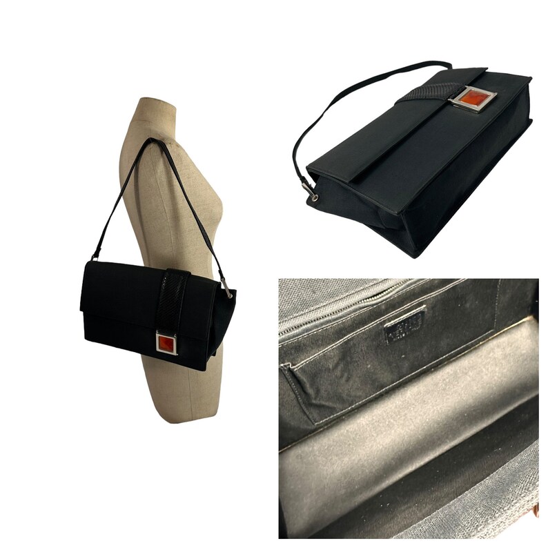 May include: Black shoulder bag with a rectangular shape. The bag features a long, thin strap and a decorative band with a red square accent. The interior of the bag is visible, showing a zippered compartment and a label.