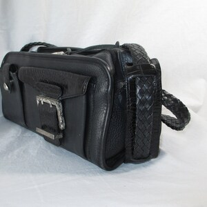 May include: A black leather handbag with a braided strap and a silver buckle.