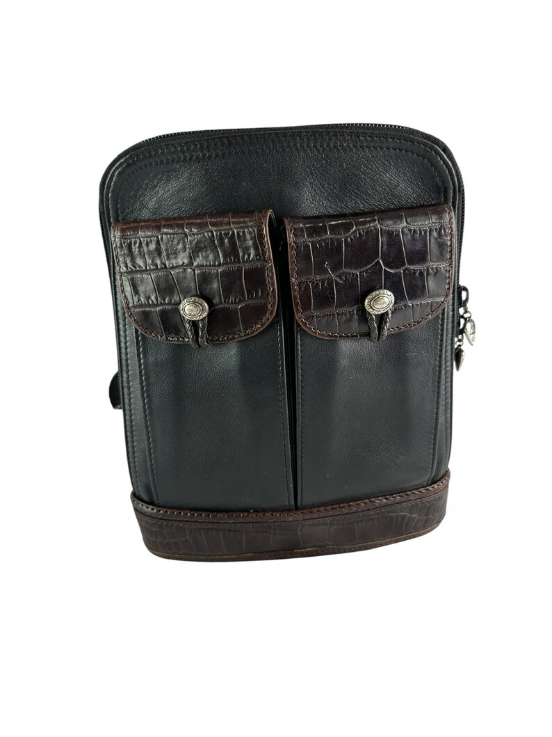 May include: Black leather crossbody bag with two front pockets featuring a brown crocodile-textured flap. The bag has a brown crocodile-textured base and silver-toned hardware. A stylish and functional accessory.