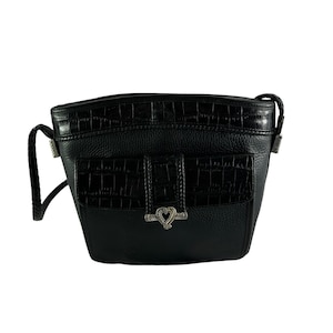 May include: Black crossbody bag with a textured leather body and a flap pocket featuring a crocodile-like pattern. The bag has a braided strap and silver-toned hardware, including a heart-shaped clasp.