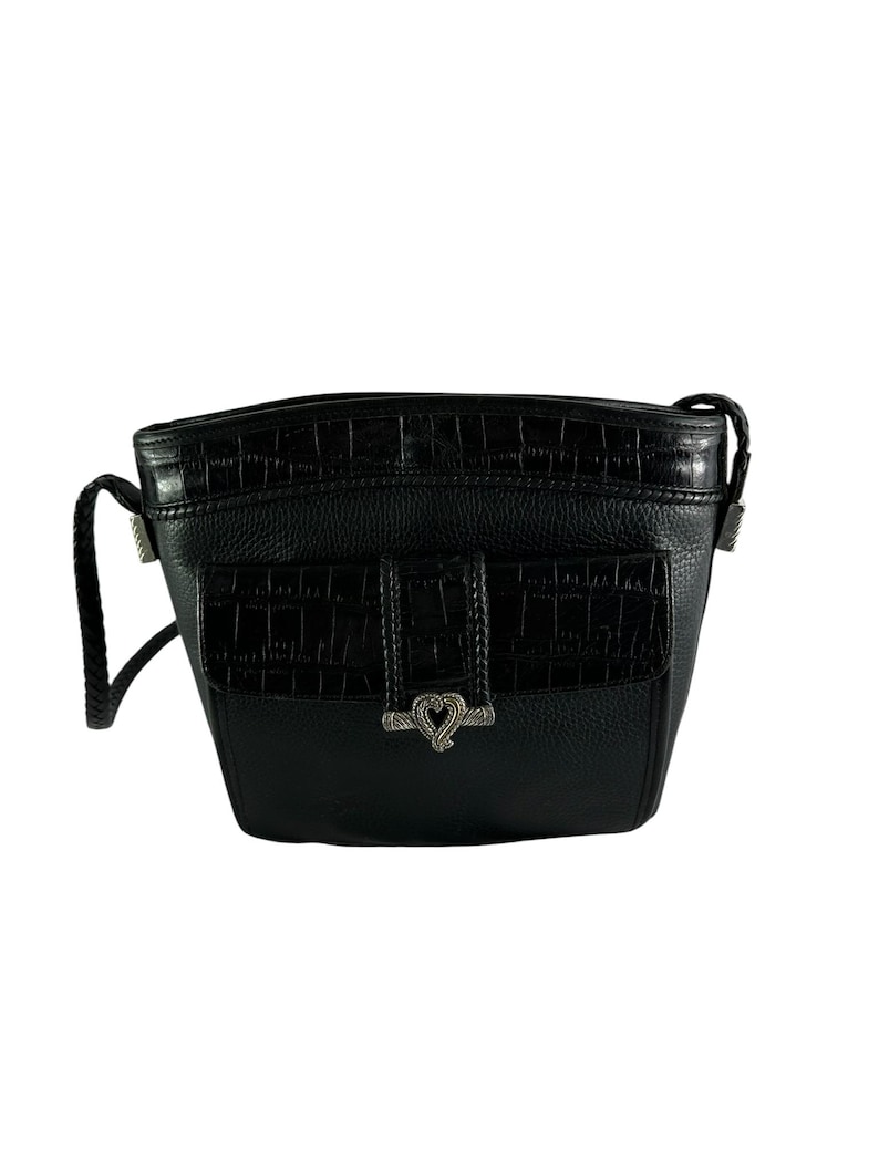 May include: Black crossbody bag with a textured leather body and a flap pocket featuring a crocodile-like pattern. The bag has a braided strap and silver-toned hardware, including a heart-shaped clasp.