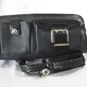 May include: Black leather handbag with a braided strap and a silver buckle. The bag has multiple pockets and a crocodile embossed detail.