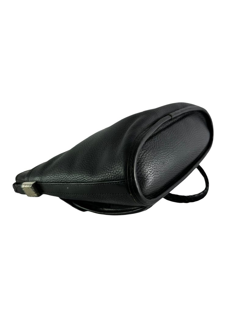 May include: Black leather shoulder bag with a rounded shape. The bag features a textured surface and a single strap. A silver-colored metal clasp is visible on the side.