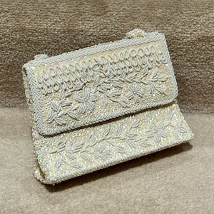 Embrague, bolso o bolso de color beige dorado claro o blanquecino con cuentas blancas y lentejuelas a juego con asa superior y bolsillo interior, retro vintage de la década de 1960