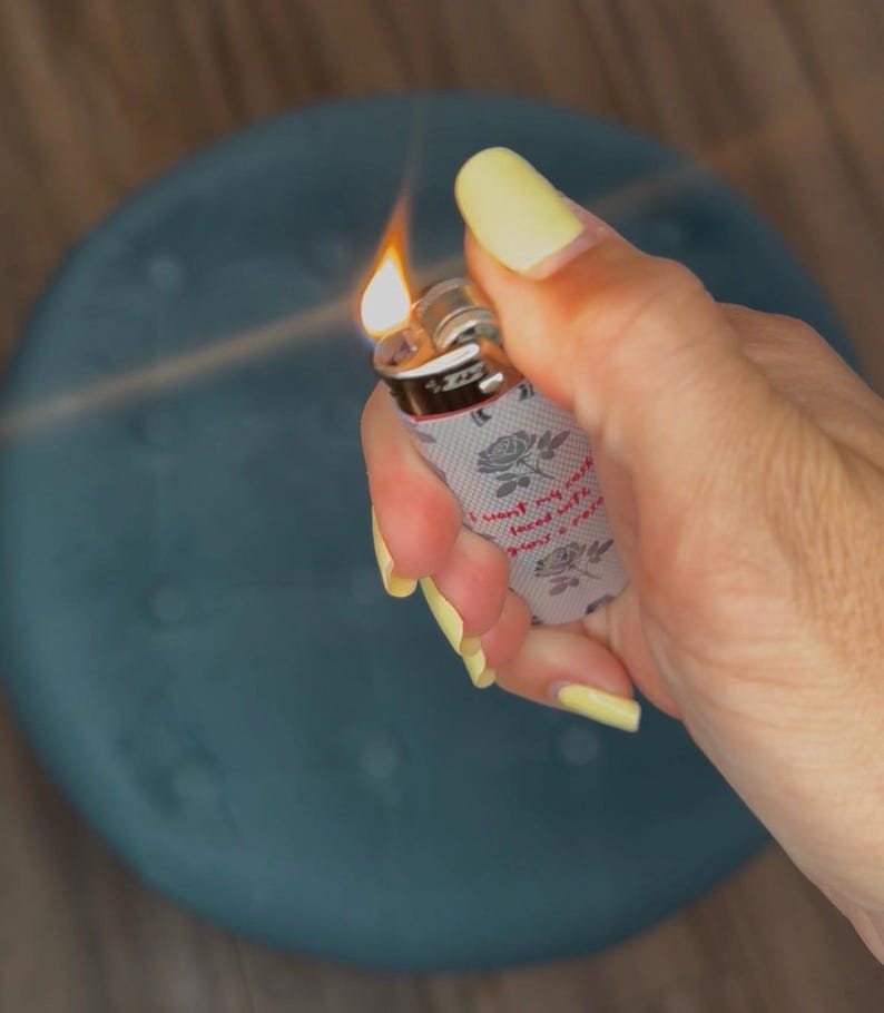 May include: A lit lighter with a floral design and the text "I want my soul faced with roses". The lighter has a gray background with roses and is held by a hand with yellow nail polish.