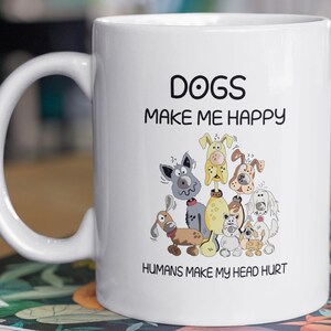 May include: White ceramic coffee mug with a black graphic of cartoon dogs and the text "Dogs make me happy, Humans make my head hurt."