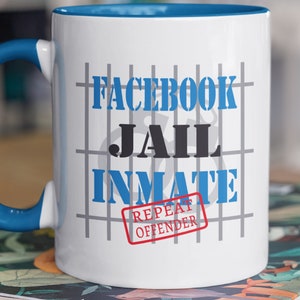 May include: White ceramic mug with a blue interior and handle. The mug features the words "FACEBOOK JAIL INMATE" in blue and black, with a jail cell grid design. A red stamp reads "REPEAT OFFENDER".