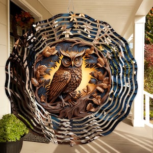 May include: A metal wind spinner with a brown owl perched on a branch in a forest scene. The owl is surrounded by leaves and branches, and the background is a dark blue with white swirls. The wind spinner is designed to spin in the wind, creating a mesmerizing effect.