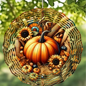 May include: A round, layered autumn decoration featuring a large orange pumpkin, sunflowers, corn, and small pumpkins. The design includes a decorative outer ring with green and brown stripes, and is suspended by a thin white string.