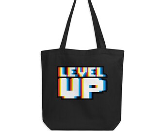 May include: Black canvas tote bag with the text "LEVEL UP" in a pixelated font with a glitch effect in rainbow colors.