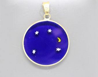 May include: A gold pendant with a blue enamel circle featuring a crescent moon and five white stars.
