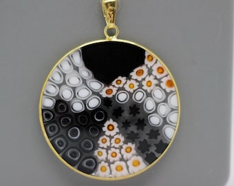 May include: A round pendant necklace with a gold frame and a black, white, and orange glass design. The glass design features a variety of patterns, including circles, stars, and flowers.
