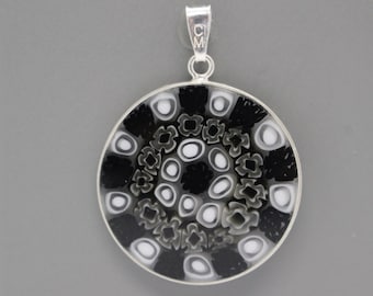 May include: A silver pendant with a black and white circular glass design. The glass features a swirling pattern of black and white circles and squares.