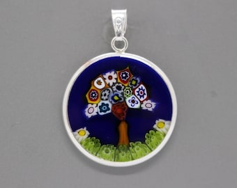 May include: A silver pendant with a round blue glass cameo featuring a colorful tree of life design.