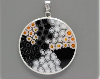 May include: A round silver pendant with a black, white, and orange glass mosaic design. The mosaic features small circles, flowers, and other geometric shapes.