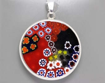 May include: A round silver pendant with a colorful Murano glass design. The glass features a variety of colors, including red, blue, black, white, and yellow. The design is made up of small flowers and stars.