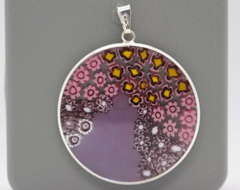 May include: A round silver pendant with a purple, pink, white, and yellow glass design. The glass design features a variety of small flowers and geometric shapes.