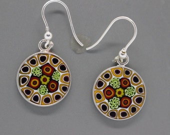 May include: A pair of silver earrings with round, colorful glass pendants. The pendants feature a geometric pattern in shades of red, orange, yellow, green, and black.