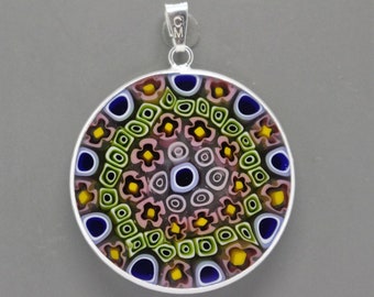 May include: A round pendant with a silver-colored frame and bail. The pendant's face features a colorful mosaic pattern with blue, yellow, green, and pink elements. The mosaic design is composed of various shapes, including circles and flower-like patterns.