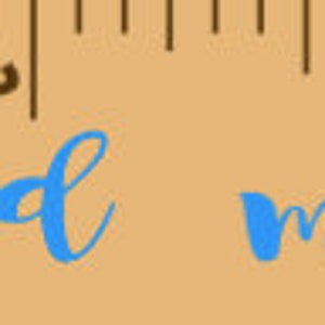 May include: A wooden ruler with the words "loved beyond measure" in blue script. The ruler also includes the name "Isaac Lang" and measurements in inches.
