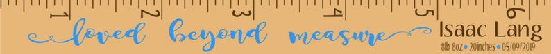 May include: A wooden ruler with the words "loved beyond measure" in blue script. The ruler also includes the name "Isaac Lang" and measurements in inches.