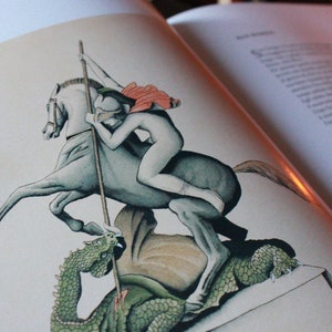 May include: A black and white illustration of a knight on horseback slaying a dragon. The knight is wearing armor and a red cape, and the dragon is green and has large wings.