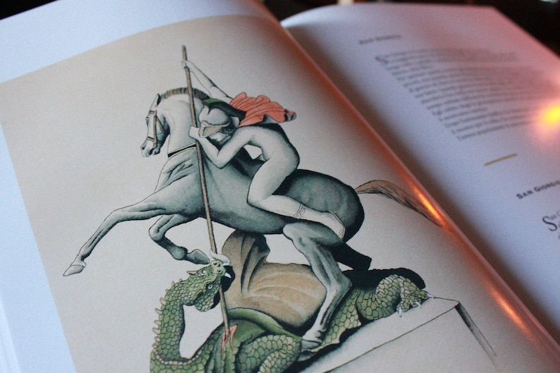 May include: A black and white illustration of a knight on horseback slaying a dragon. The knight is wearing armor and a red cape, and the dragon is green and has large wings.
