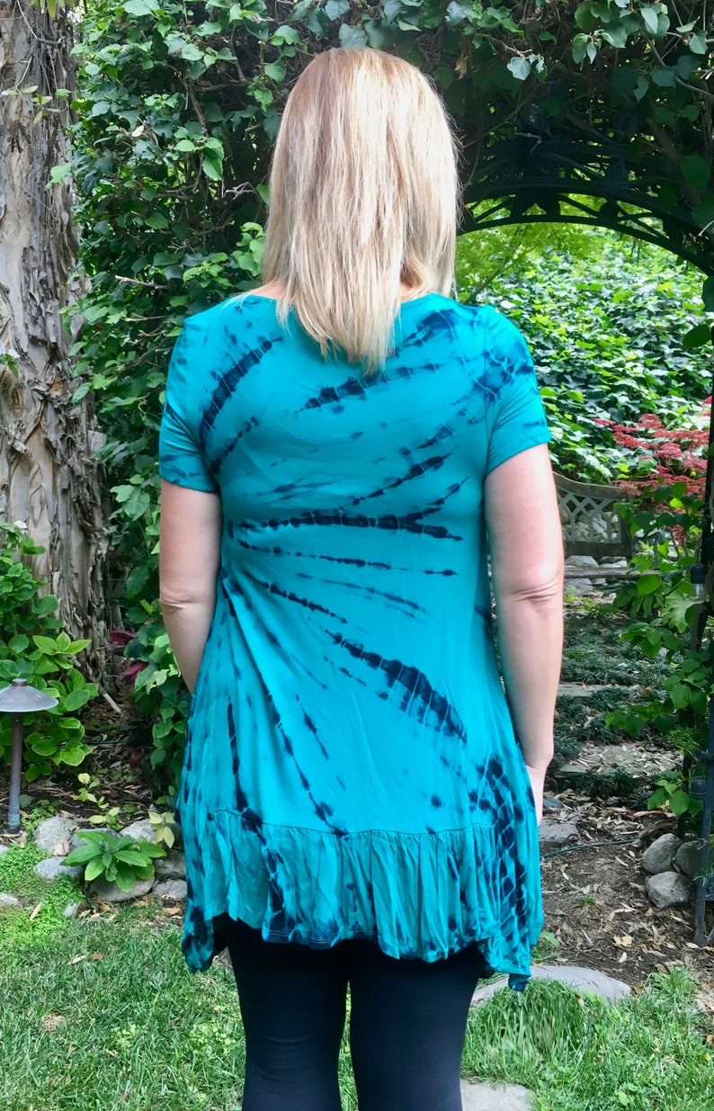 May include: A turquoise tie-dye tunic with a ruffled hem. The tunic has a scoop neck and short sleeves.