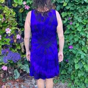 May include: A purple and black tie-dye sleeveless dress with a swirling pattern. The dress is knee-length and has a relaxed fit.