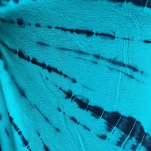 May include: A turquoise fabric with a black tie-dye pattern. The fabric has a soft, textured surface.