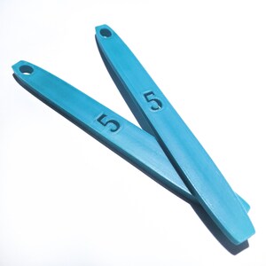 May include: Two blue plastic measuring spoons with the number "5" printed on them.