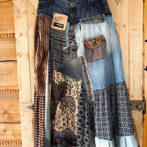 Può includere: Una gonna patchwork in denim con una varietà di tessuti, tra cui denim, velluto marrone e tessuti fantasia. La gonna presenta una chiusura con bottoni, tasche e un mix di trame e motivi, creando un'estetica bohémien.