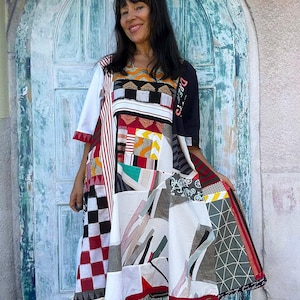 Peut inclure: Une robe arrivant aux genoux présentant un motif patchwork avec divers imprimés, notamment des carreaux rouges et blancs, des rayures noires et blanches, des formes géométriques et des motifs de vélos. Une manche est blanche et l'autre noire.