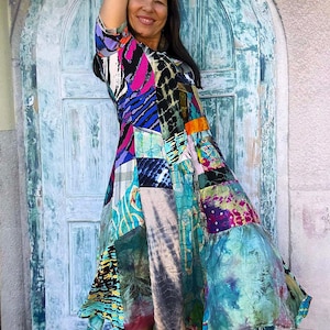 Könnte beinhalten: Ein knielanges Kleid mit Patchwork-Design und verschiedenen bunten Mustern, darunter Batik, abstrakte Formen und Streifen in Blau-, Rosa-, Schwarz-, Orange- und Grüntönen, mit kurzen Ärmeln und einem ausgestellten Rock.