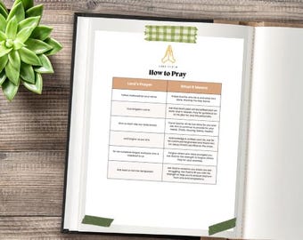 Può includere: Libro aperto con una pagina stampata intitolata "How to Pray" con una tabella di testo. La pagina è fissata al libro con nastro adesivo washi verde. Una pianta succulenta verde si trova nell'angolo in alto a sinistra.