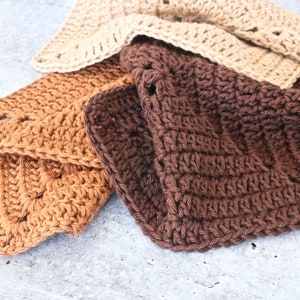 May include: Three crocheted dishcloths in brown, tan, and beige. The dishcloths are made with a simple stitch pattern and have a textured surface.