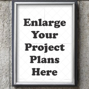May include: A framed sign with the text "Enlarge Your Project Plans Here" in bold, black letters. The sign has a silver frame and is mounted on a textured, gray stone wall. The background of the sign is white with a subtle diamond pattern.