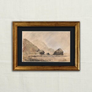May include: A framed landscape art piece featuring a sepia-toned coastal scene. The artwork depicts rolling hills and rock formations under a cloudy sky. The frame is gold-colored, and the artwork is set against a black mat.