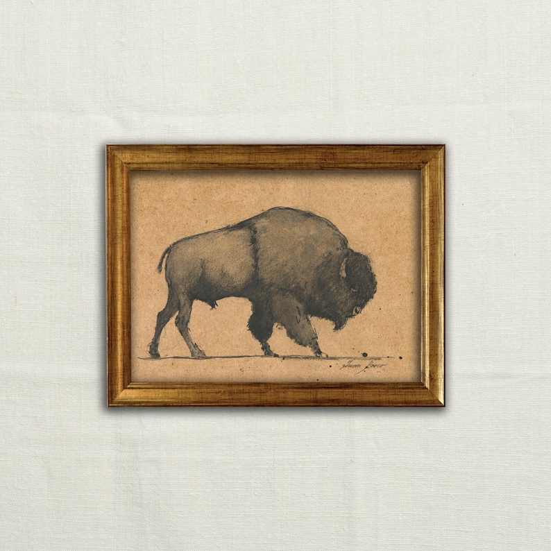 May include: A framed print featuring a detailed charcoal drawing of a bison. The artwork is set against a tan background and enclosed in a gold-colored frame. The bison is depicted in profile, showcasing its large size and shaggy fur.