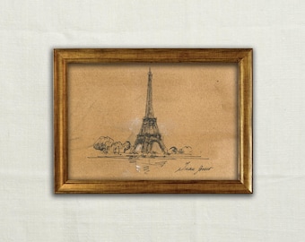 May include: A framed sketch of the Eiffel Tower rendered in black ink on tan paper. The artwork is enclosed in a rectangular gold-toned frame with a metallic finish. The drawing features the tower structure and trees, with a signature in the corner.